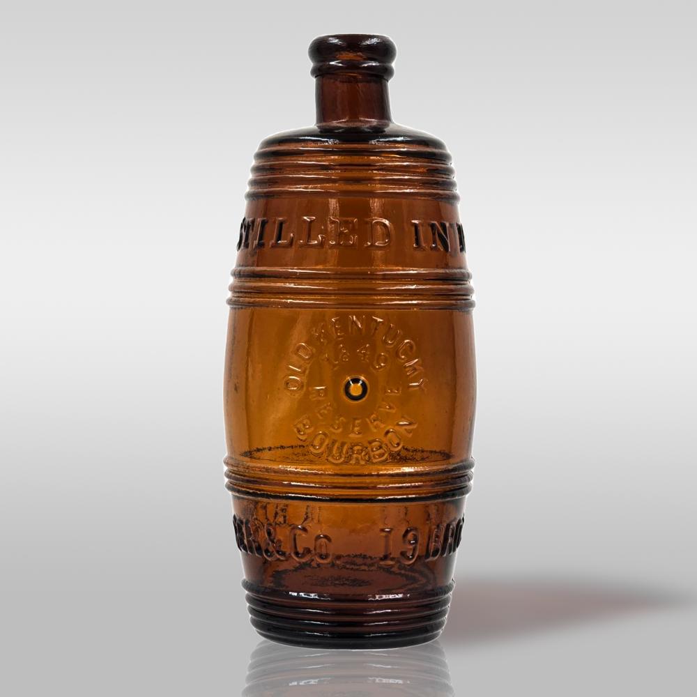 Amber glass figural whiskey bottle with ribbed body and raised decorative banding; open neck shown against a light background.