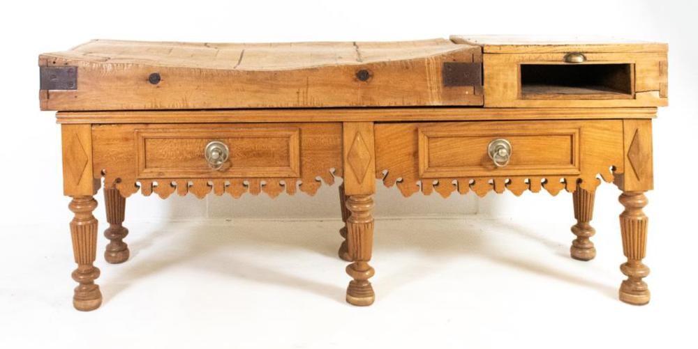 Antique-style wooden butcher block table with a drawer, drawer front knobs, and scalloped apron detailing on turned legs.