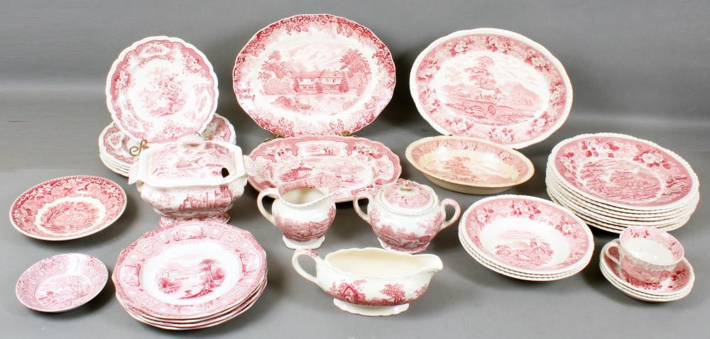 Group of red-and-white ironstone dinnerware with scenic transfer-print designs, including plates and pitchers on a gray background.
