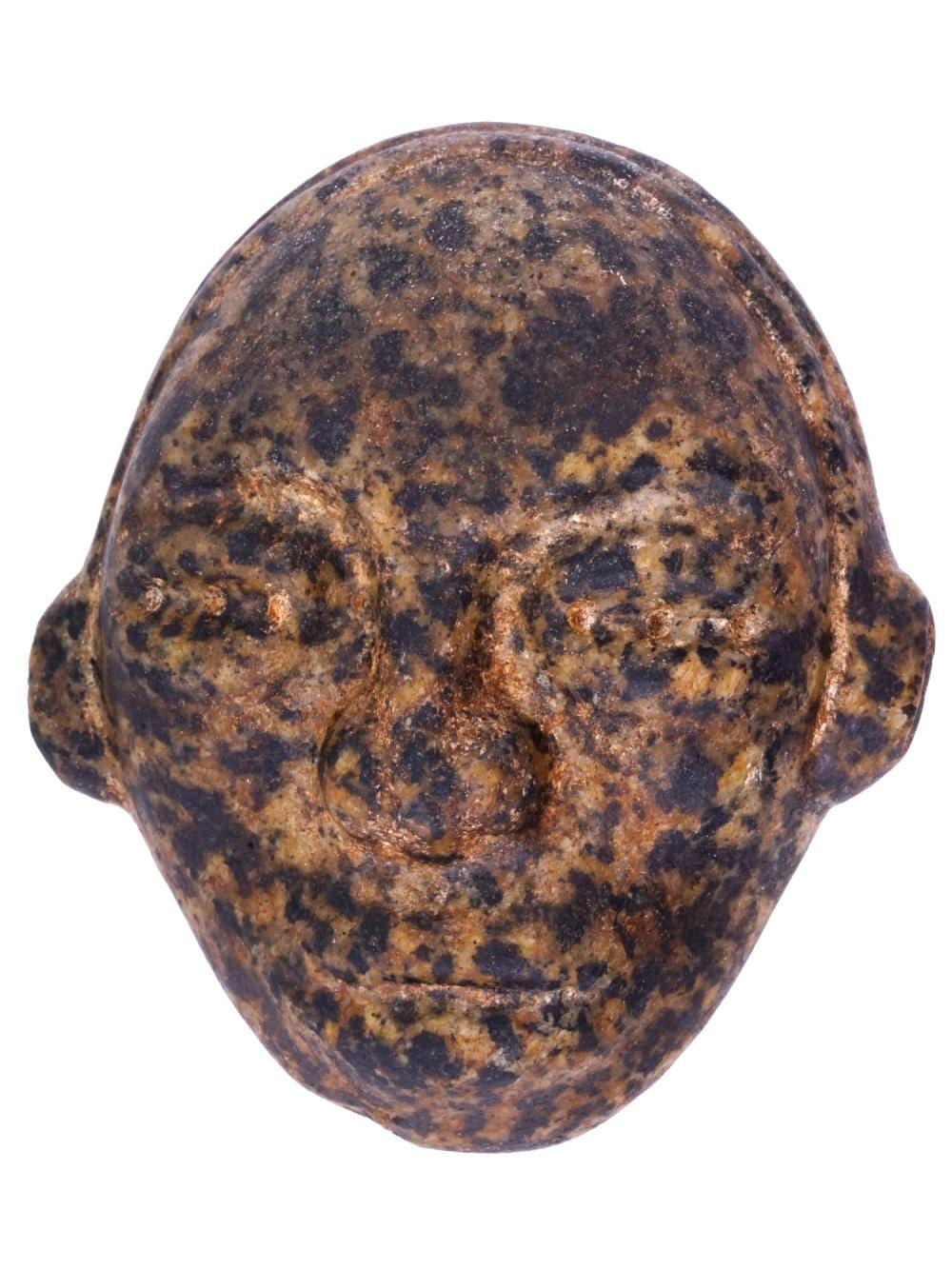 Carved stone mask with a rounded head and dark speckled surface on a white background.