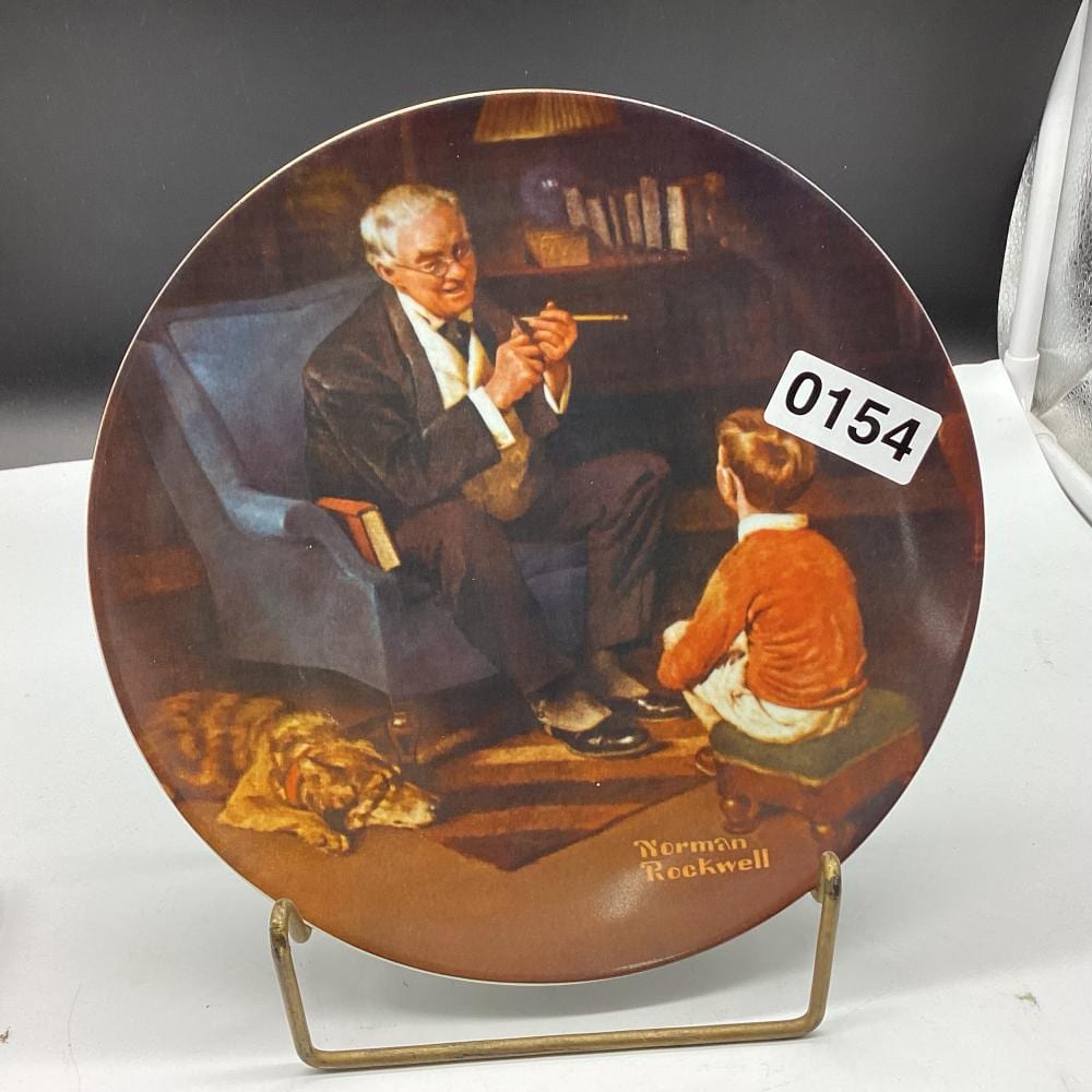 Decorative collector plate with an illustration of a suited man speaking to another person, plus “Norman Rockwell” text at the bottom.