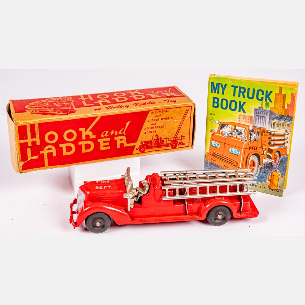 Red vintage toy fire truck with ladder and a front book, shown with its box labeled “Hook and Ladder” and “My Truck Book.”