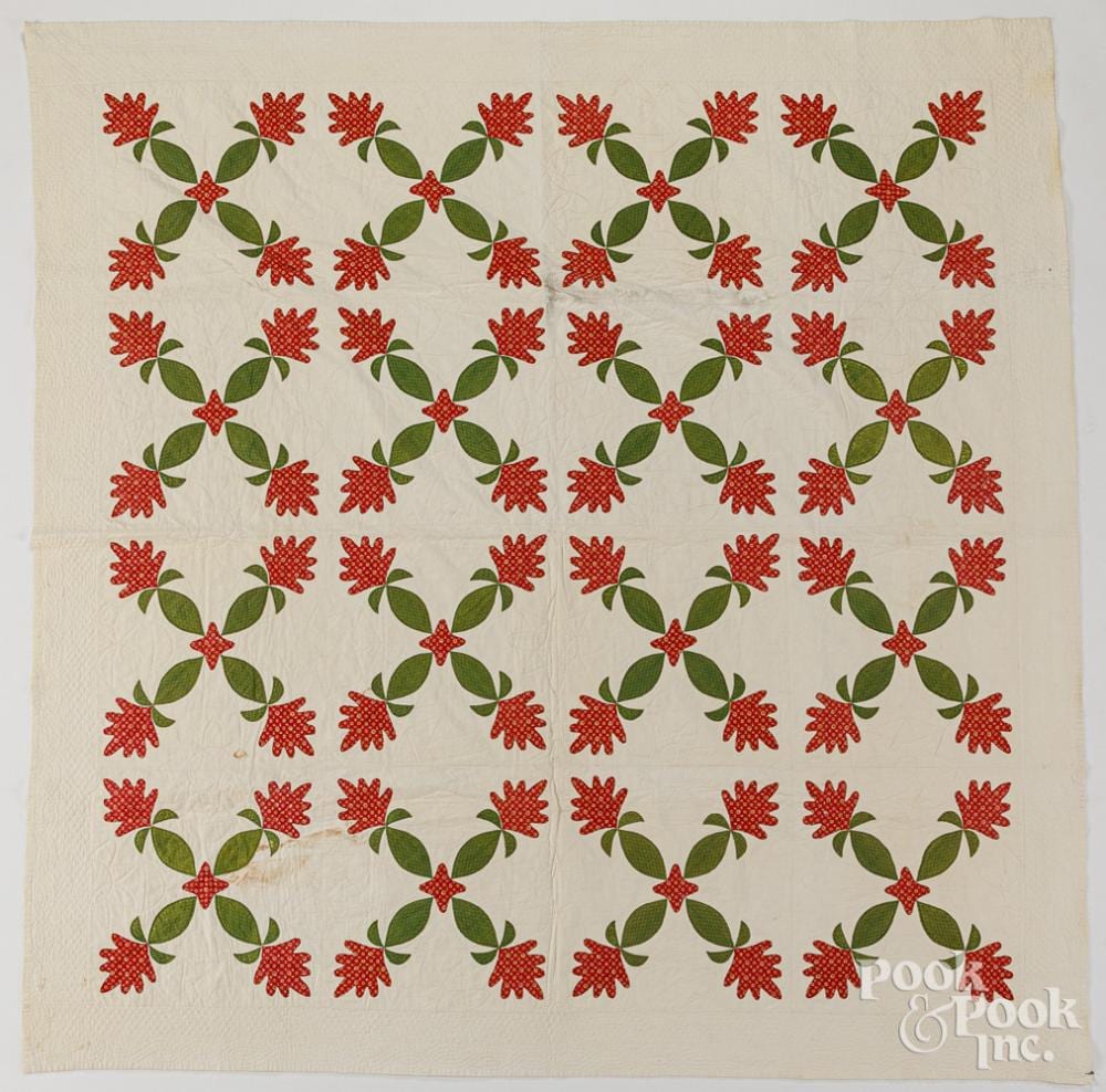 Cream quilt panel with repeated red floral appliqué wreaths and green leaves across the surface.