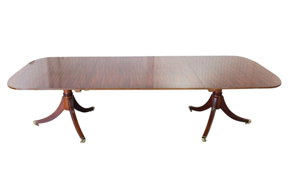 A craftsman-made George III-style crossbanded mahogany twin pedestal dining table, 20th century, possibly by Brights of Nettlebed, with "D" shaped ends and two leaf inserts, supported by a pair of pedestals with gun barrel columns and inverted... sold by Dawsons Auctioneers, lot 124 — auction record photograph