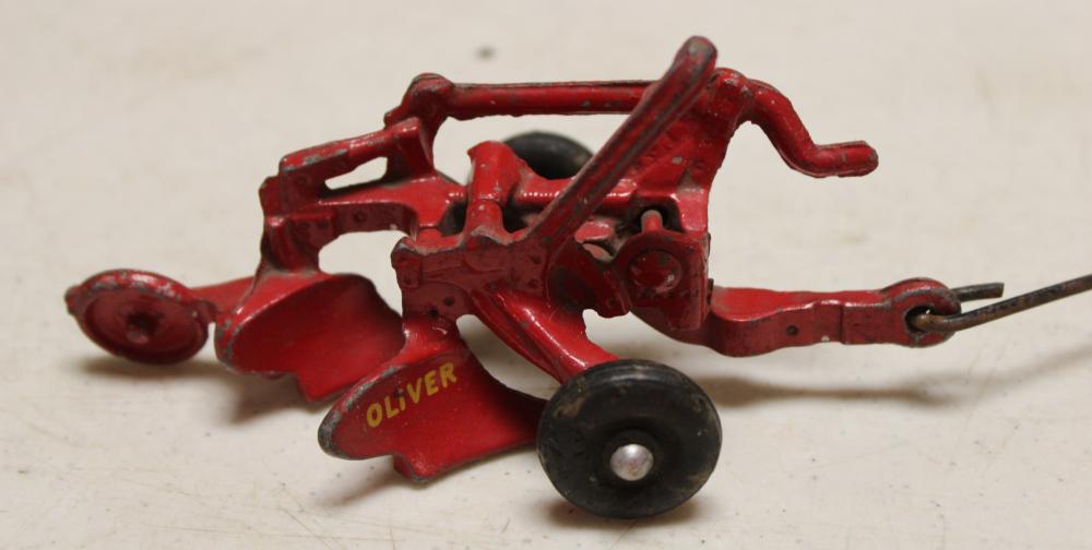 Red and black cast metal toy tractor with a plow attachment, side view, with yellow “Oliver” lettering on the front.