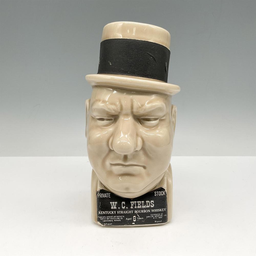 White and tan porcelain novelty bottle shaped like W.C. Fields’ face with a black top hat and printed label reading “PRIVATE STOCK.”