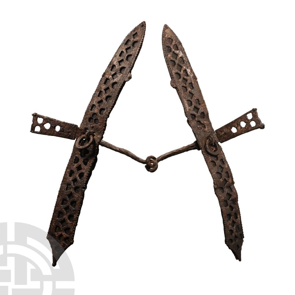 Rust-colored iron horse bit with two vertical bars and decorative cutouts, connected by a central chain loop.