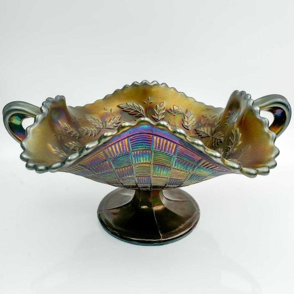 Yellow-green carnival glass bowl with two loop handles and leaf-and-fan decoration in iridescent rainbow colors.