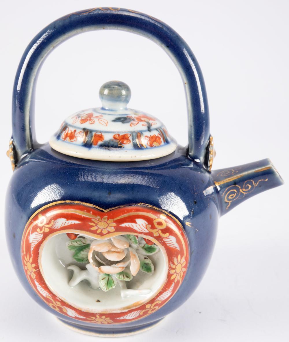 A Japanese Imari porcelain teapot, to each side a recessed panel, one with chicken, rooster and eggs, the other with flowers, all set against a powder blue ground, highlights in gilt, associated non-matching Chinese Imari cover, Japan, Edo period (16 sold by Heritage Auctions Europe, lot 387 — auction record photograph