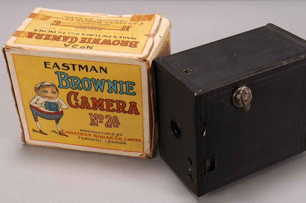 Black Kodak Brownie camera body beside a box labeled “Eastman Brownie Camera No 2A.”