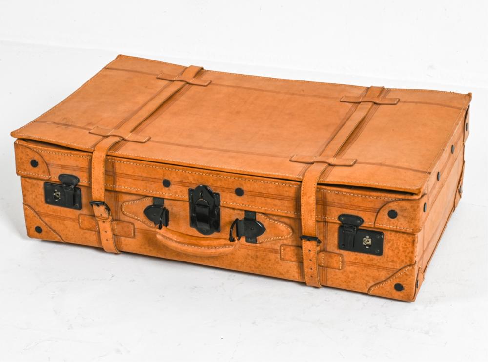 Vintage tan leather suitcase with black metal latches, multiple straps, and a hinged top lid.