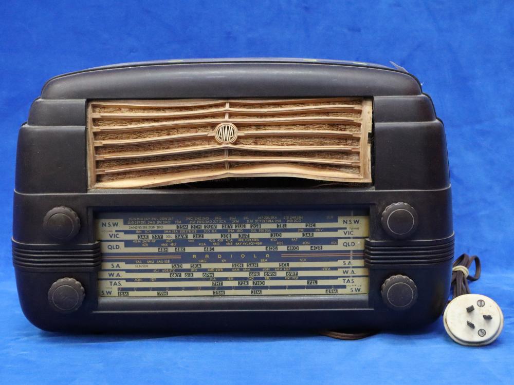 Front view of a black vintage AWA Art Deco-style bakelite radio with tuning dial and speaker grille on a blue background.
