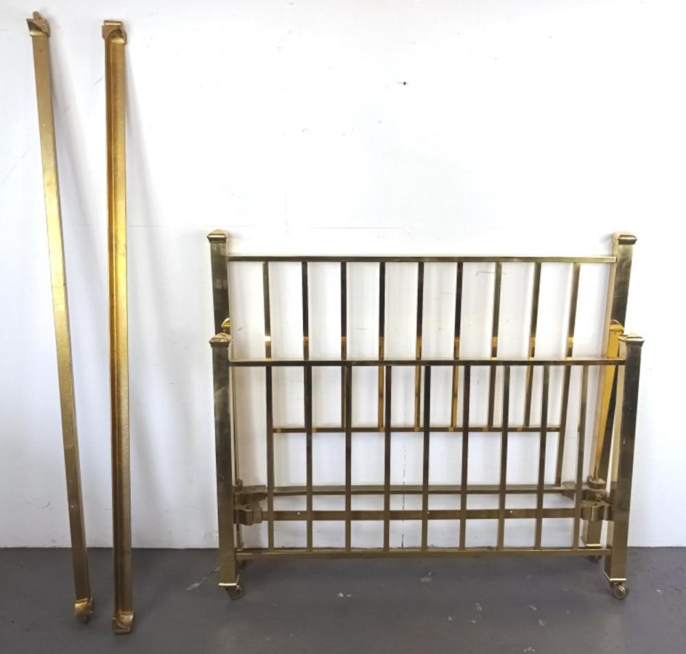 Brass full-size bed frame with vertical slats and posts, photographed against a plain white wall.