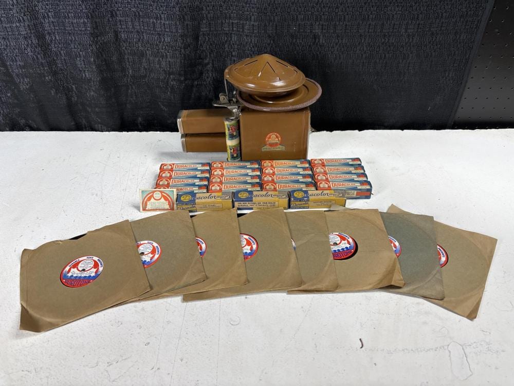 Vintage toy film projector setup with stacked boxed rolls and multiple paper sleeves on a table, photographed against a dark backdrop.