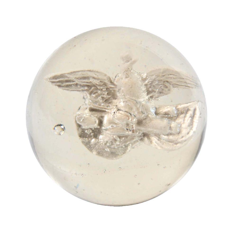 Round gemstone-like cabochon with a raised metallic eagle design and blue cabochon accents on a white background.