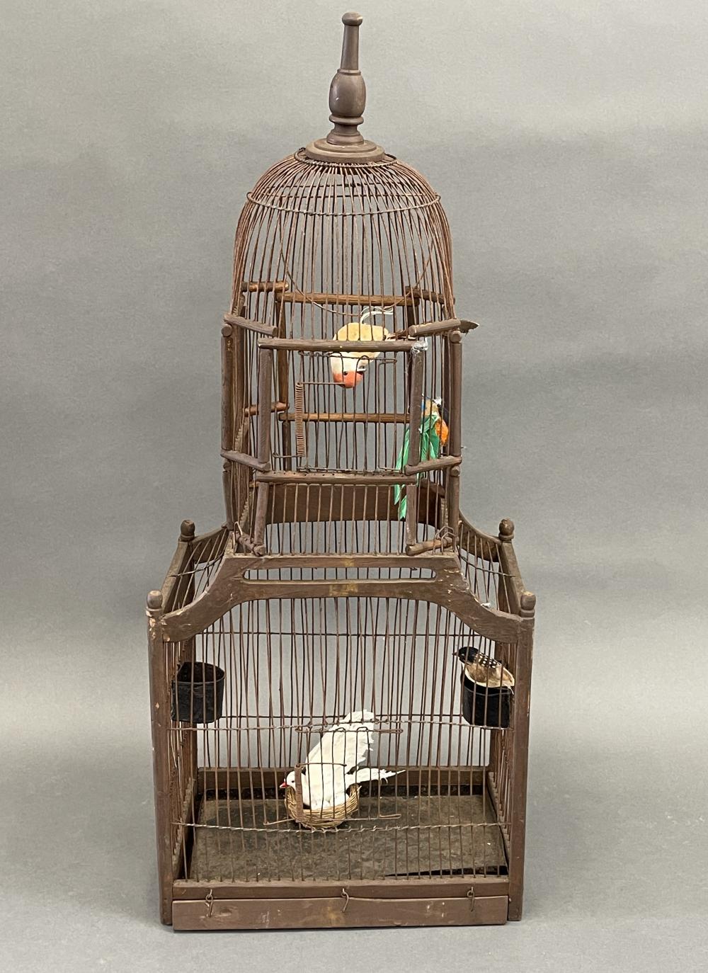 Victorian-style birdcage with arched wire bars, a round top, and interior perches holding two small birds.