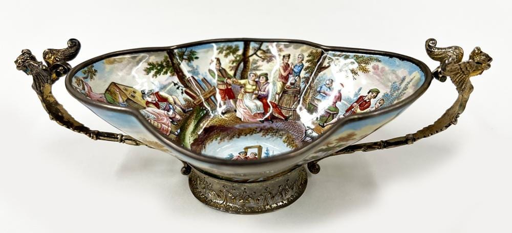 Enamel candy dish with raised gold-tone rim and sculpted handles, decorated with a painted pastoral scene and figures around the edge.