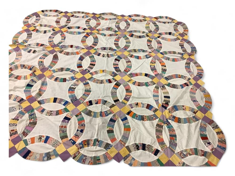 Colorful fabric quilt top with white oval and star-shaped patches arranged in a repeating pattern.