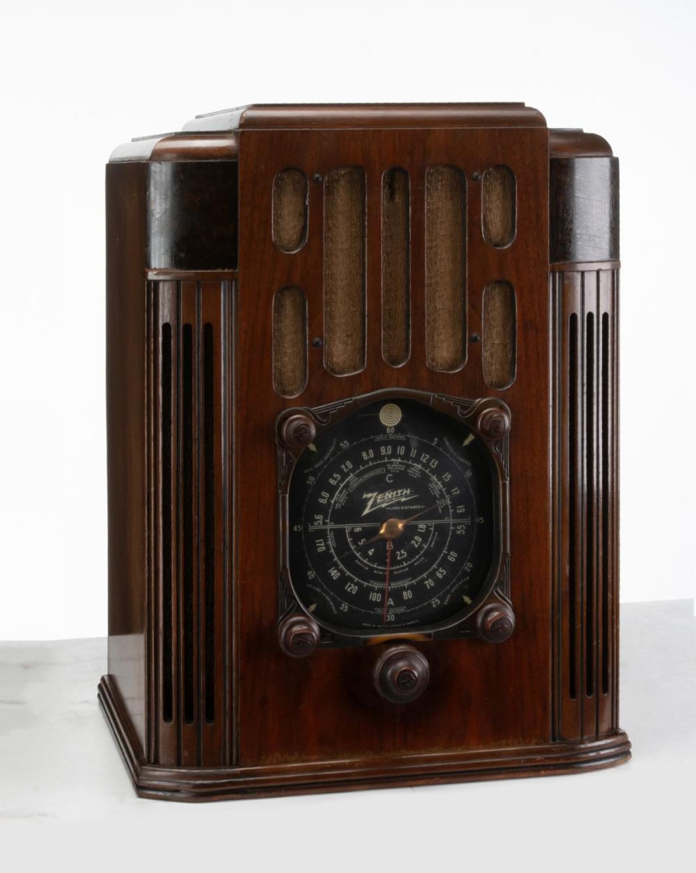 Front view of a vintage wooden Zenith radio with vertical grille panels and a circular tuning dial.