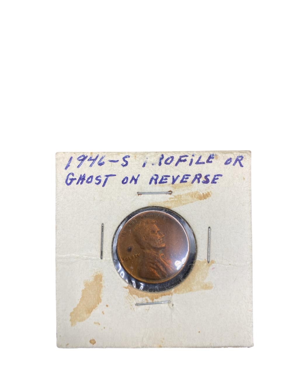 Photograph of a copper coin centered on a white card, with handwritten blue text above it and magnifying marks around the coin.