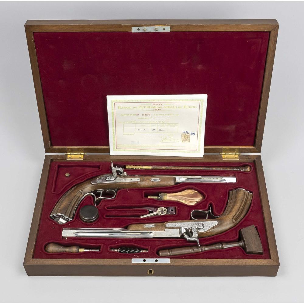A pair of dueling pistols displayed inside a wooden case with a burgundy velvet lining and an included paper label.