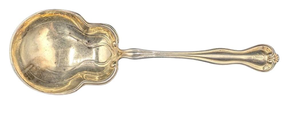 Sterling silver gilt-wash ladle with a rounded, engraved bowl and an ornate handle, photographed against a white background.