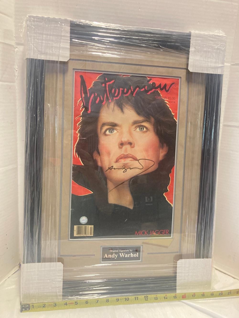 Framed poster print featuring a close-up portrait of Mick Jagger with red and black graphic background and a visible black signature on the face.