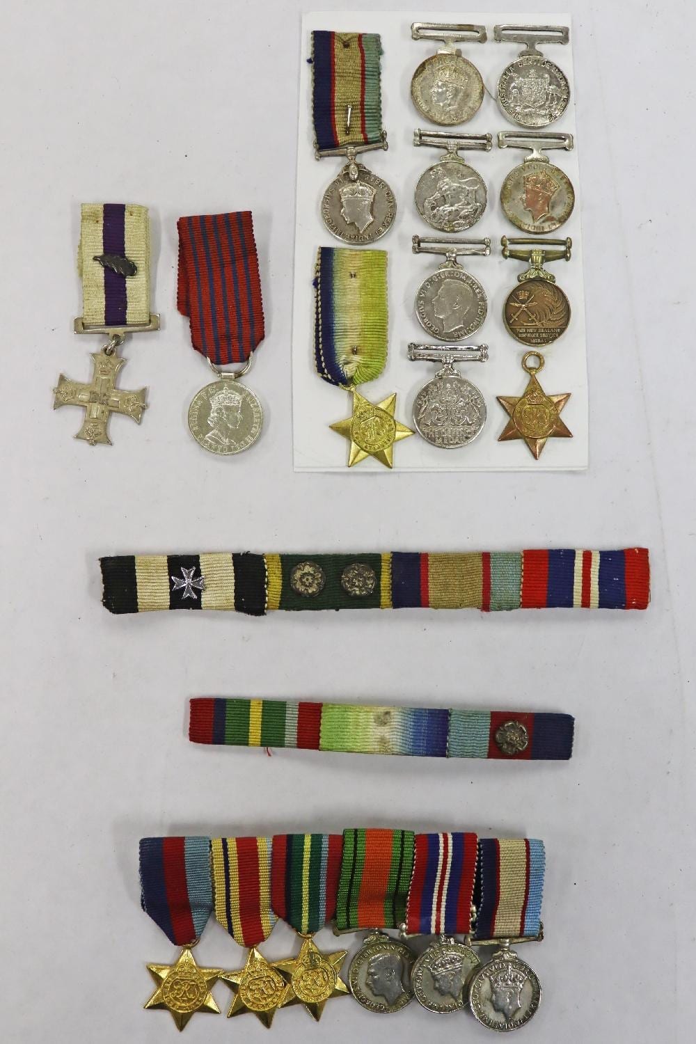 Group of miniature military medals on ribbon bars, with several round medals and star-shaped badges displayed on a white background.