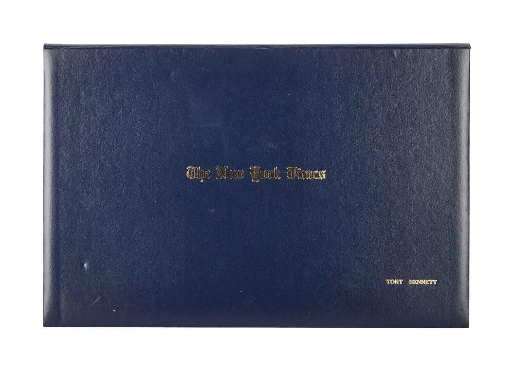 Closed blue folder or album cover with gold text reading “The New York Times” and smaller “TONY BENNETT” near the bottom right.