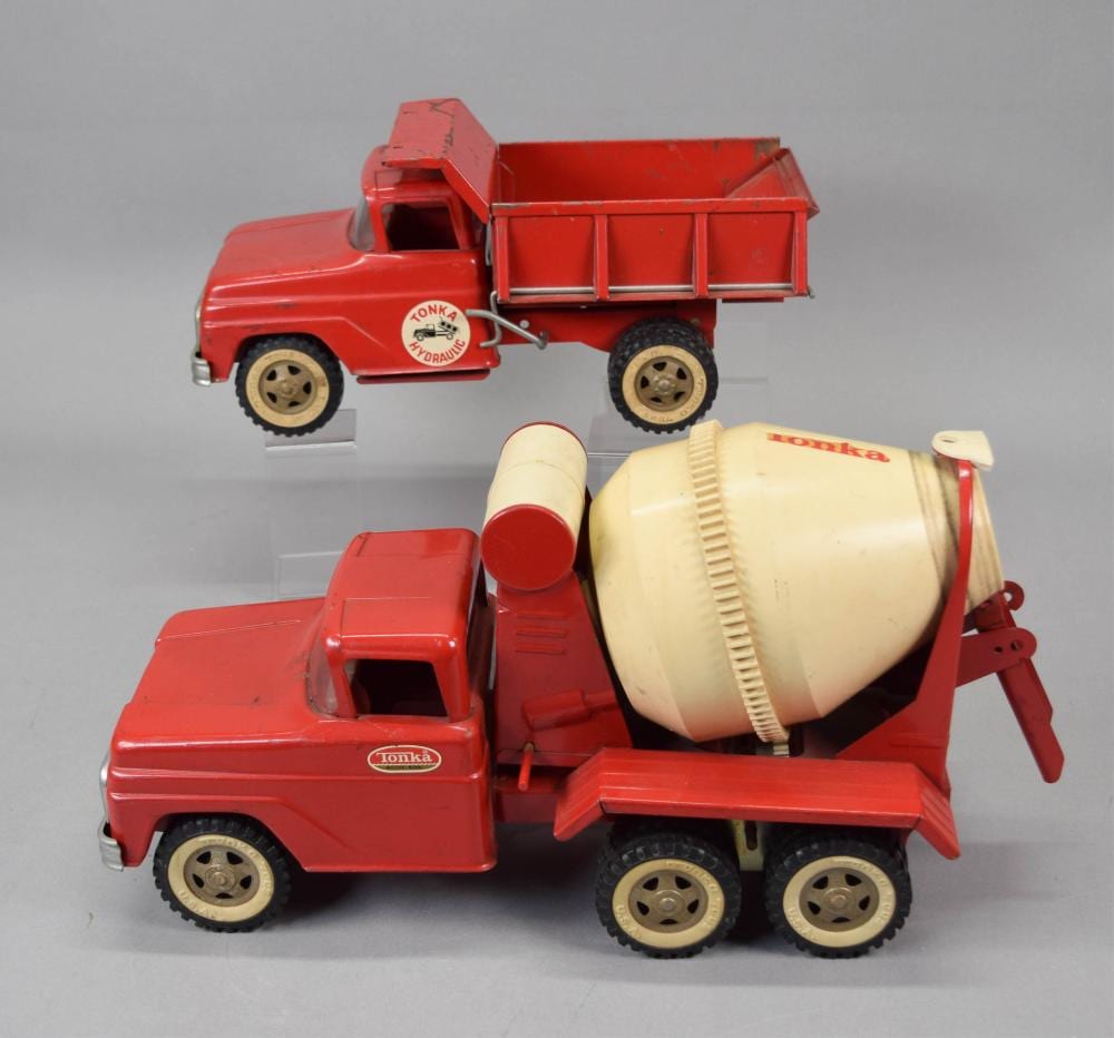 Red and cream toy cement mixer truck with rotating drum and beige wheels, photographed against a gray background.