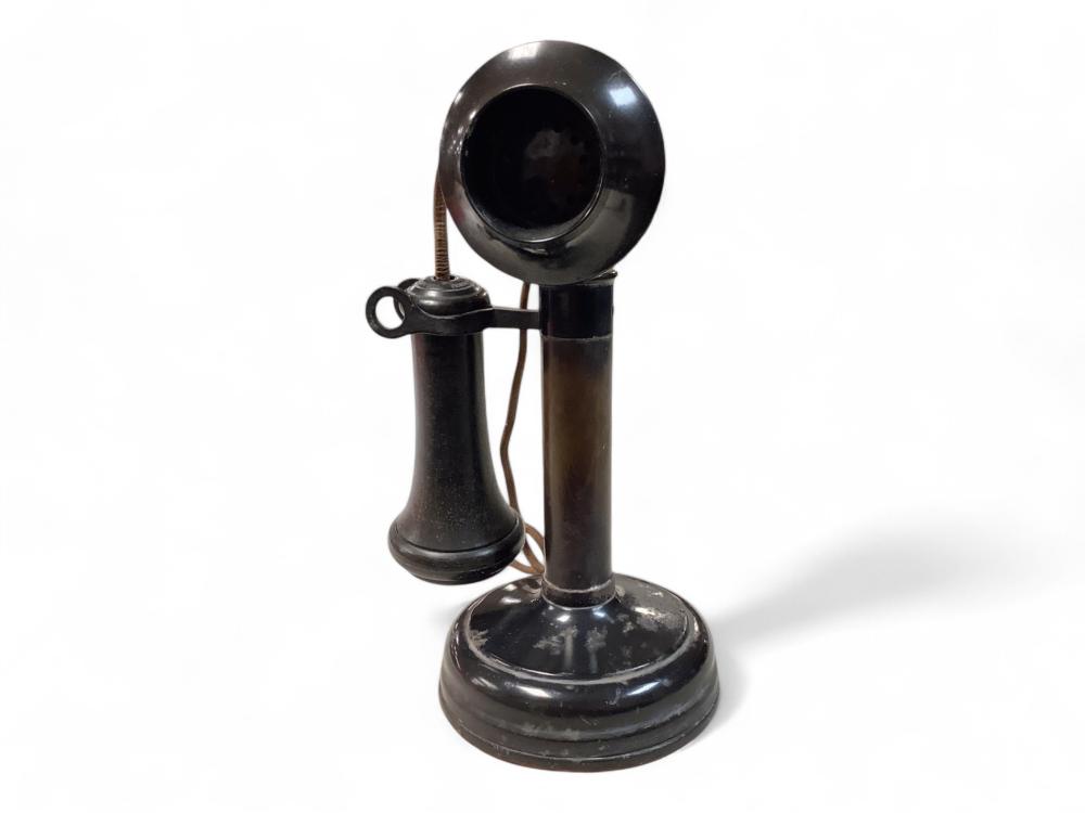 Antique-style candlestick telephone handset and base with a dark metal finish and coiled cord.