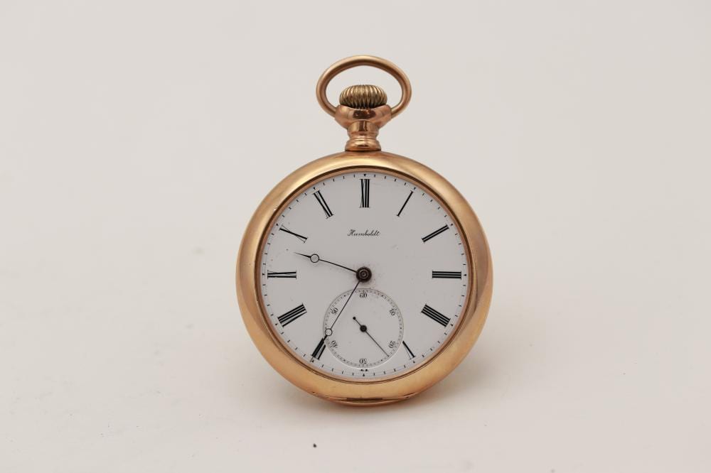 Gold-tone open-face pocket watch with a round case, hanging loop, and white dial with black Roman numerals and sub-dial.