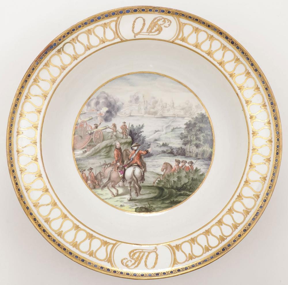 Porcelain bowl with a gold and blue patterned rim and an oval scene painting of riders on horseback in a landscape.