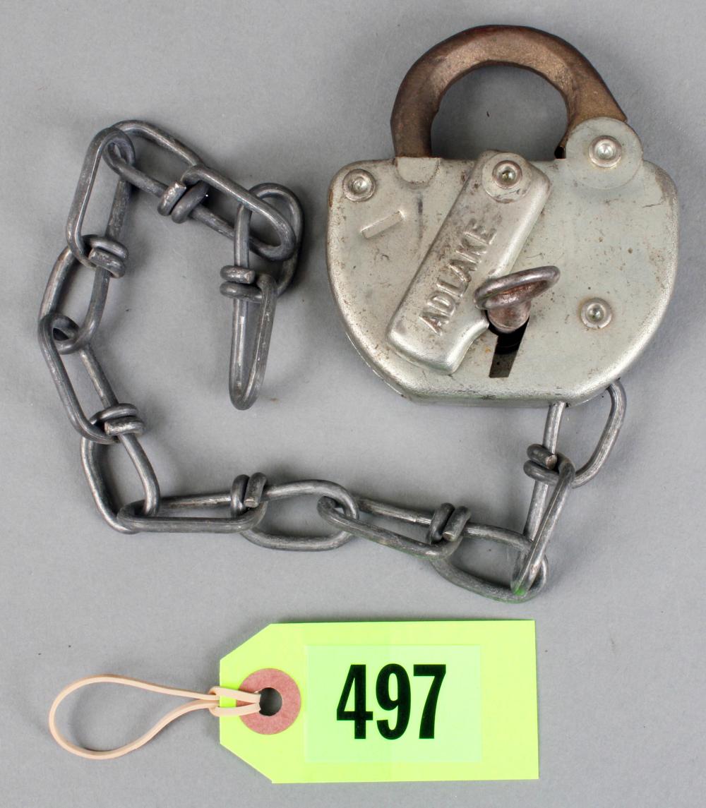 Metal padlock with chain and a small key on a light gray background; key tag label with the number 497 is visible at the bottom.
