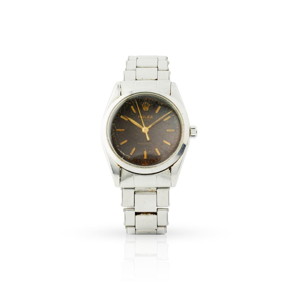 Front view of a stainless steel wristwatch with a dark dial and gold-tone hour markers, on a white background.