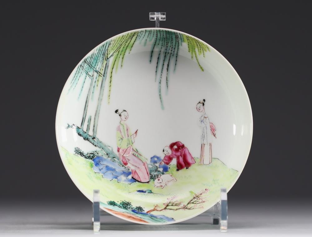 Chinese porcelain plate with colorful children and animals scene in pink, green, blue, and red on a white background.