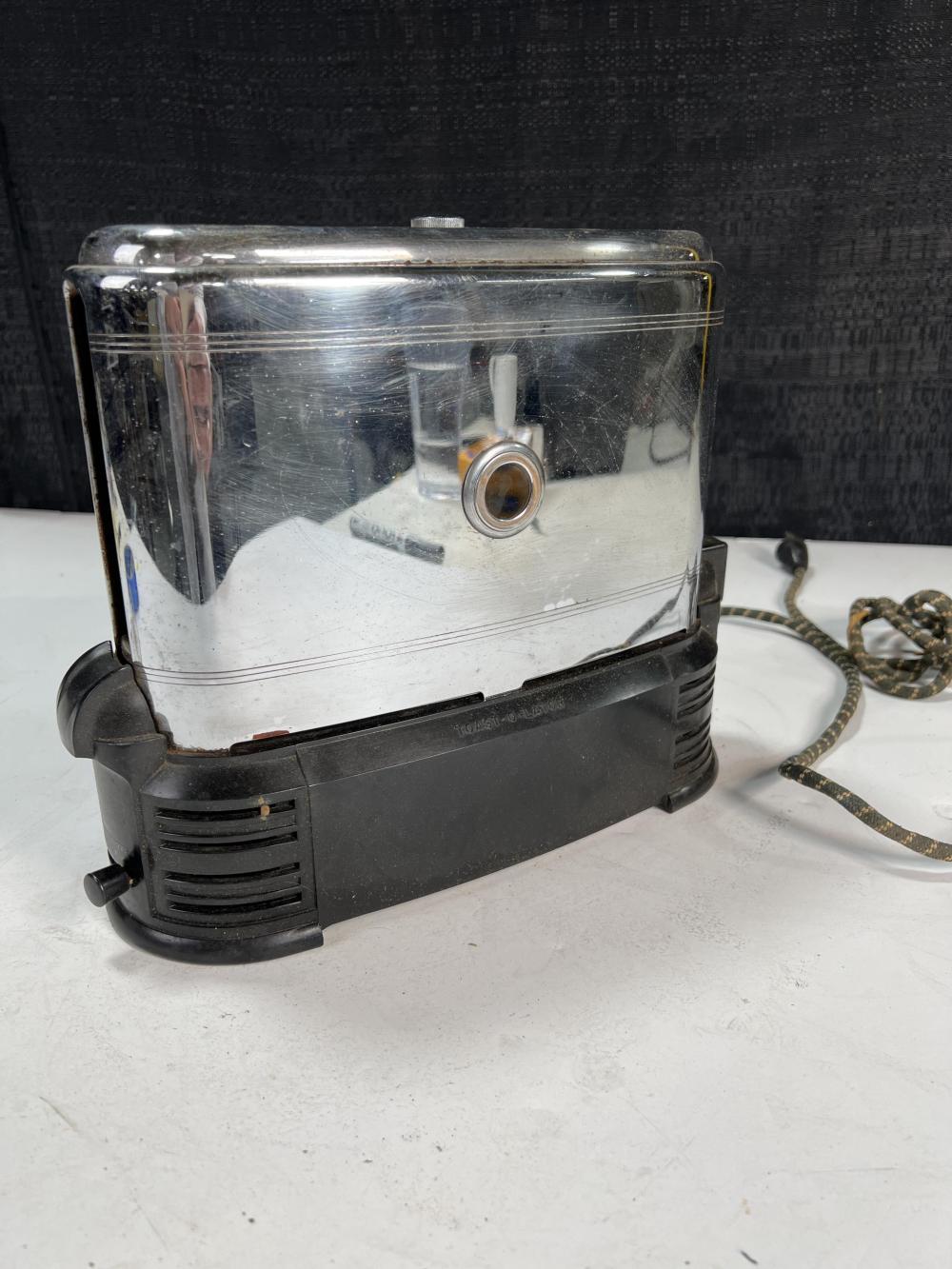 Chrome narrow-slot toaster with a clear heating chamber and black plastic base, photographed on a white surface.