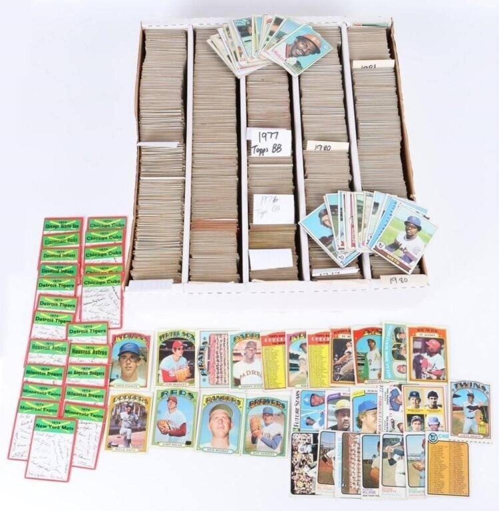 Large group of vintage baseball trading cards spread out and stacked in a box, with colorful player portraits and team branding.