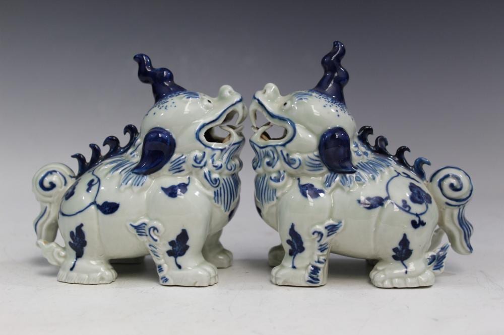 Pair of blue-and-white porcelain foo dog figurines with open mouths, raised front paws, and decorative swirling patterns.