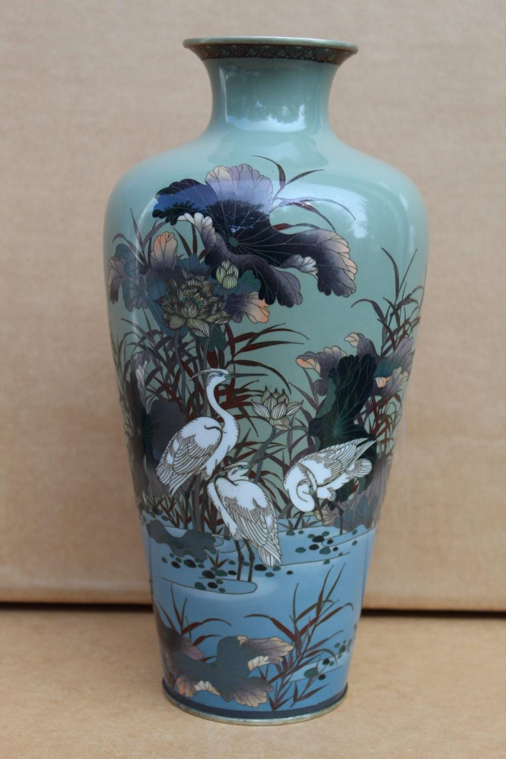 Blue Japanese cloisonné vase with floral decorations and white birds in a garden scene.