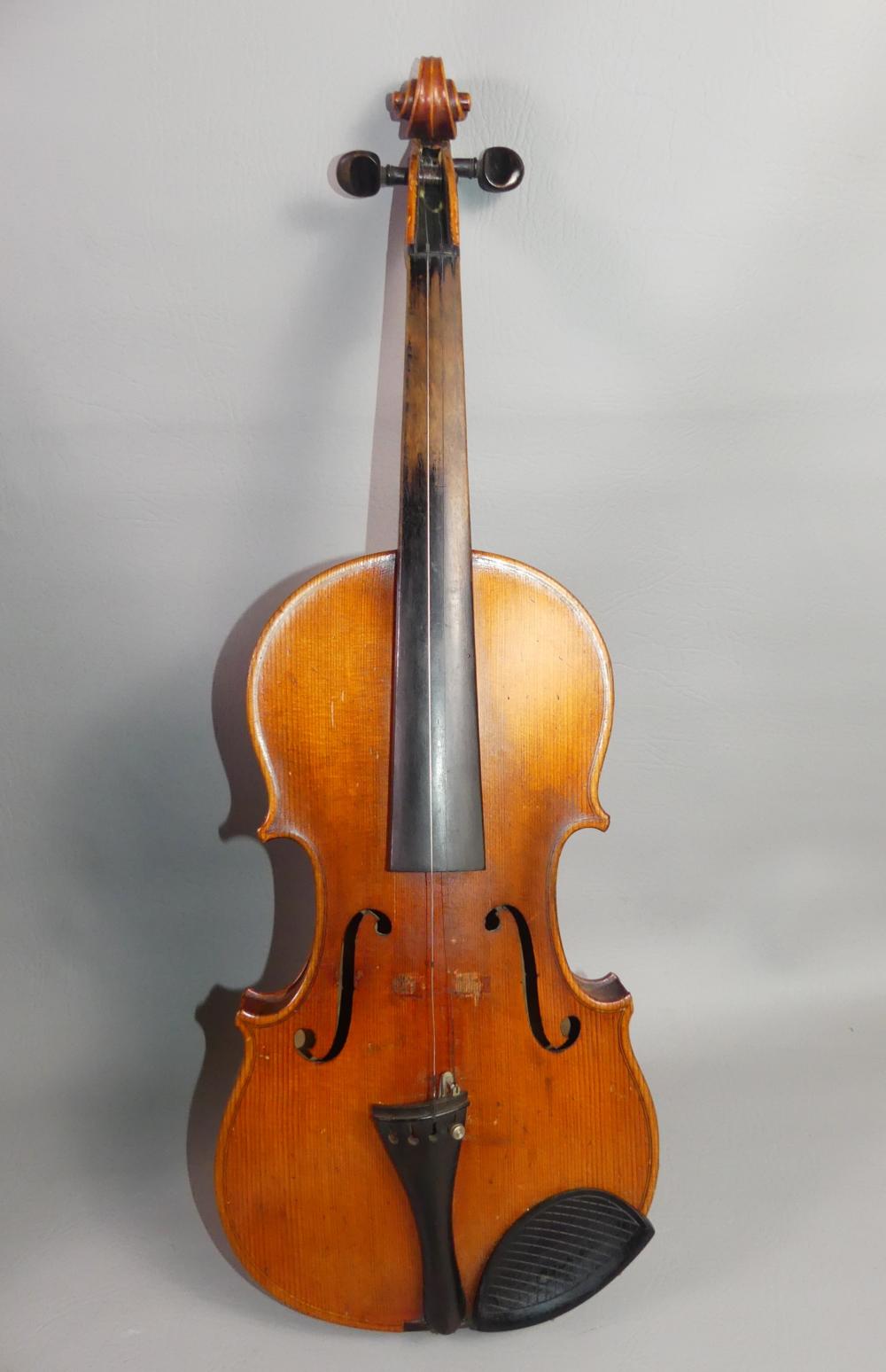 Antique wooden violin standing upright against a plain light background.