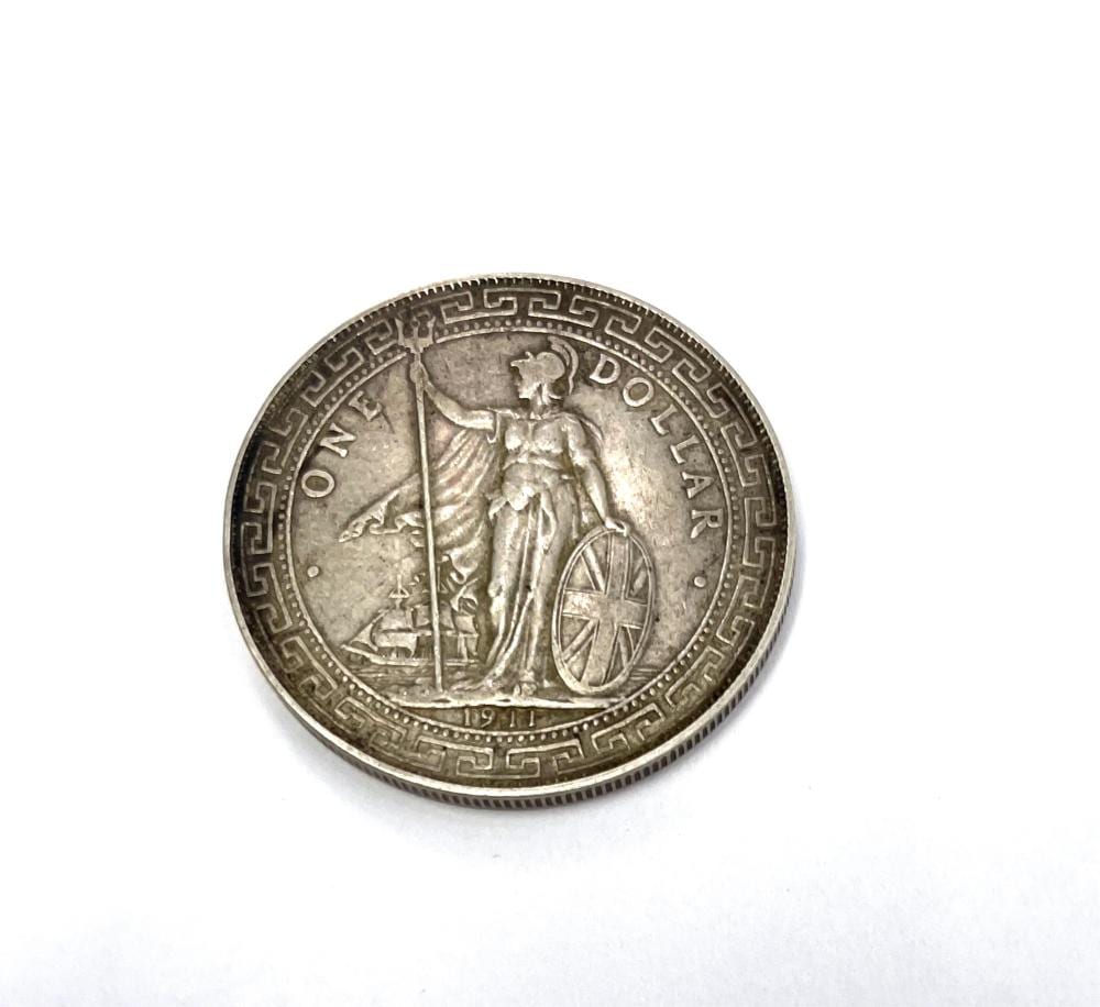 Silver-colored coin showing a standing figure holding a flag, with decorative border and the year 1911 on the bottom.