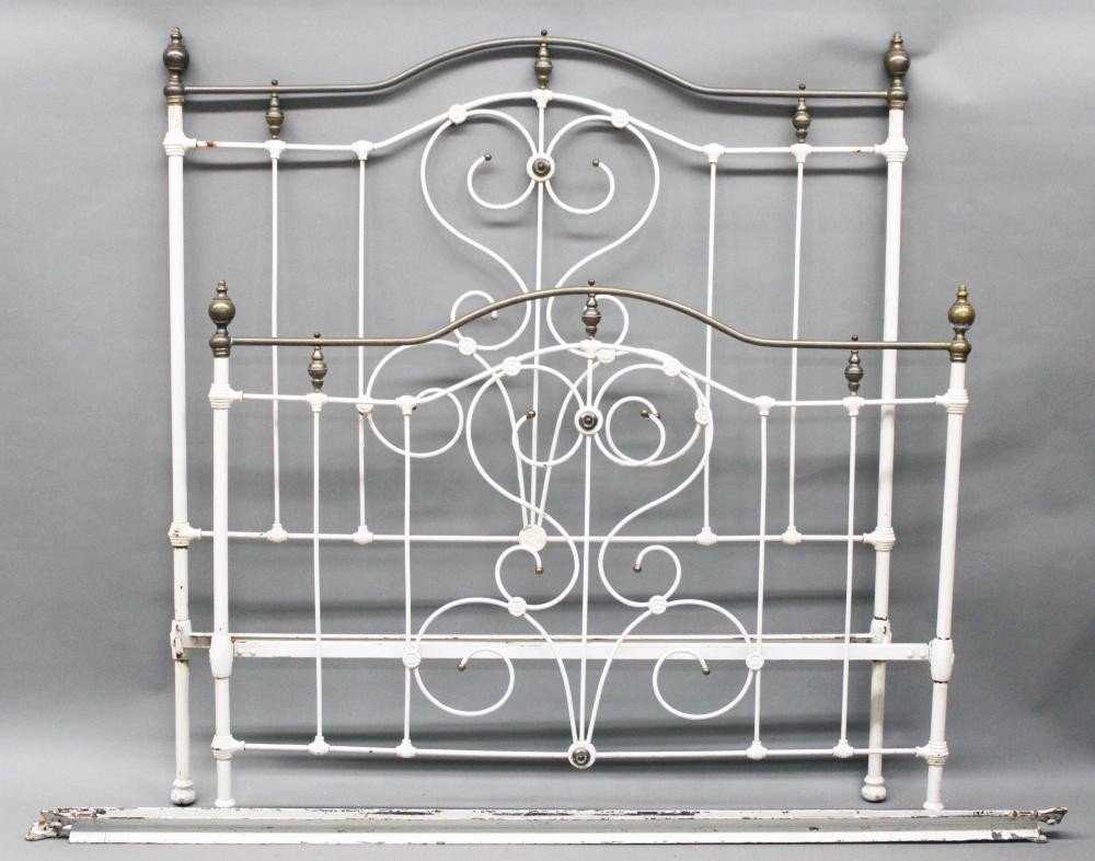 White and brass antique metal bed frame headboard and footboard with scrollwork and finials.