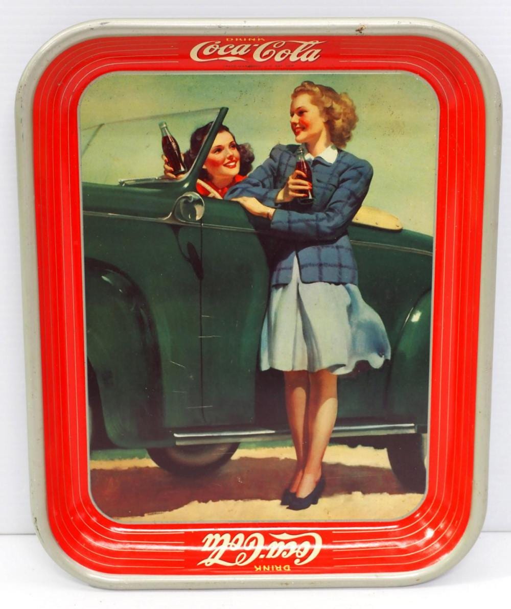 Vintage Coca-Cola serving tray with a red border and illustrated scene of two women holding bottles near a car.