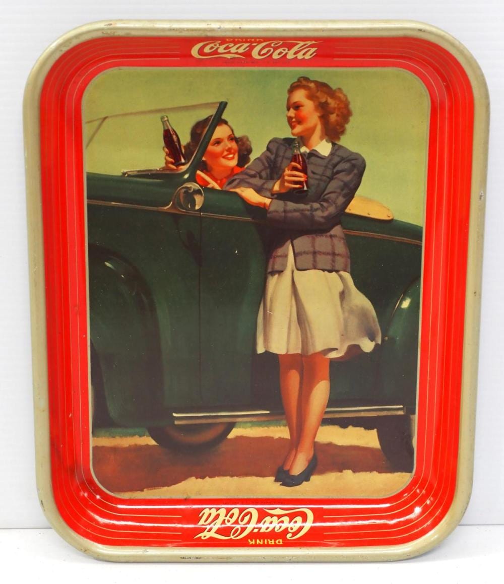 Vintage Coca-Cola serving tray with a red rim and illustration of two people holding bottles over a black drink cooler background.