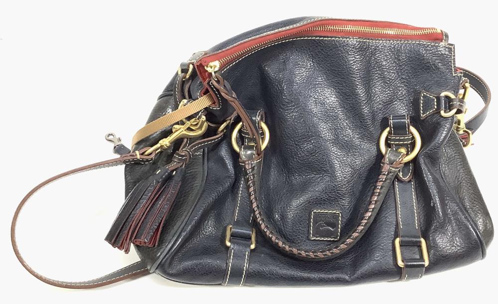 Black leather designer handbag with red-lined zipper top, tassel key fob, gold-tone hardware, and a crossbody strap.