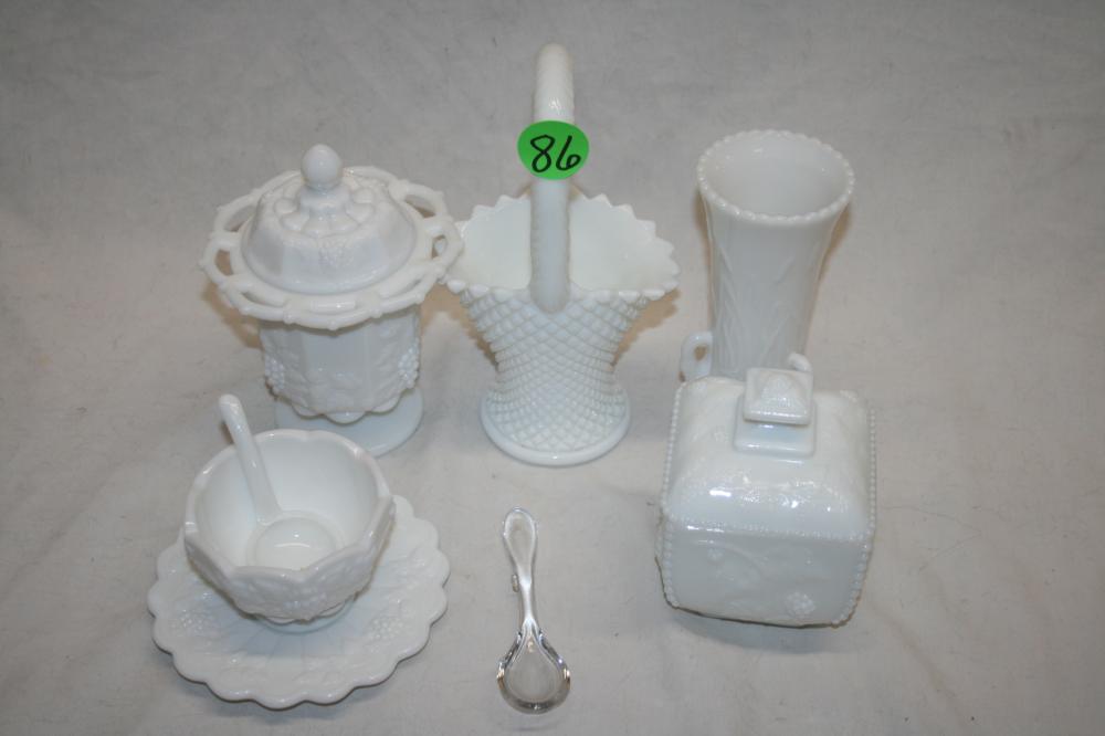 Collection of white milk glass serving pieces including lidded tureen, basket, vase, and a cloche-like container on a light surface.