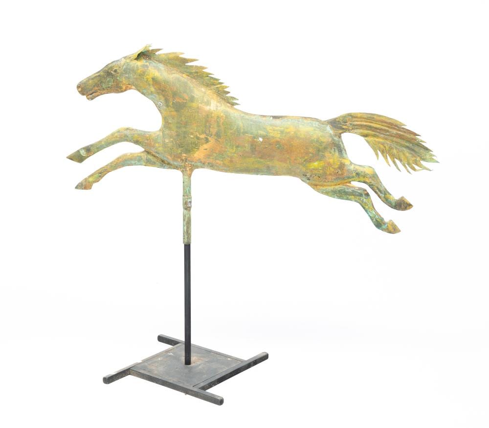 Metal horse weathervane with a raised forelock and outstretched wings, mounted on a vertical pole on a rectangular base.