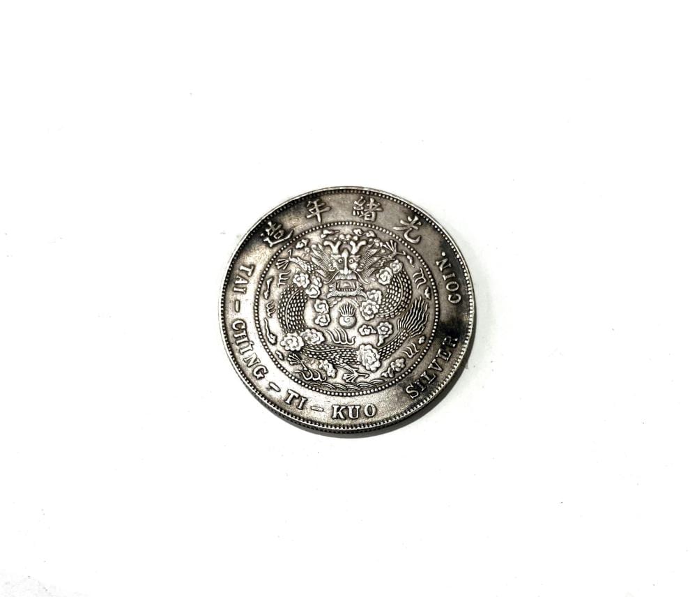 Silver-colored Chinese coin with a dragon design and surrounding Chinese characters, photographed on a white background.