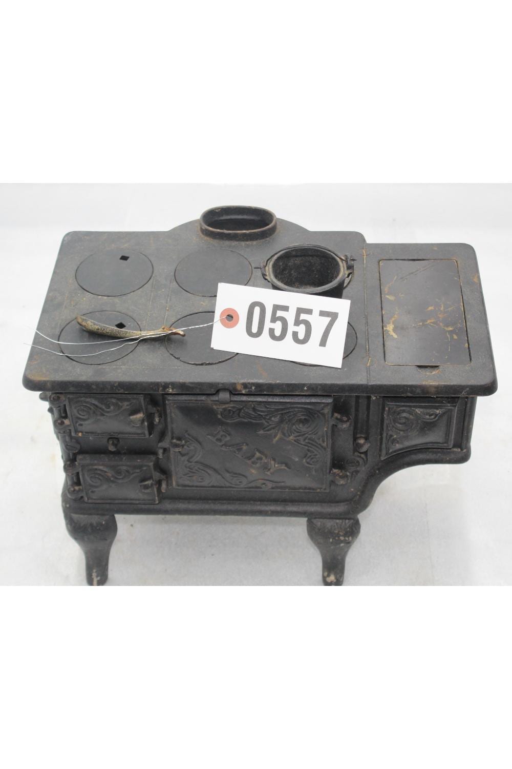 Cast iron toy stove with four round burner covers and embossed panel details, photographed on a white background.